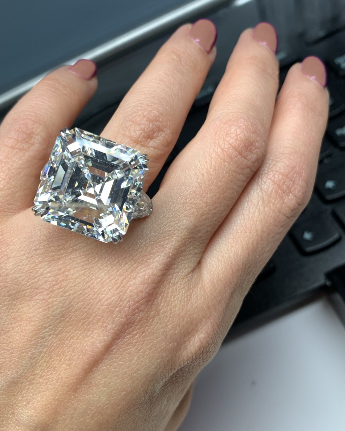 Large square step-cut diamond with cropped corners in a thin white gold halo, worn on the hand