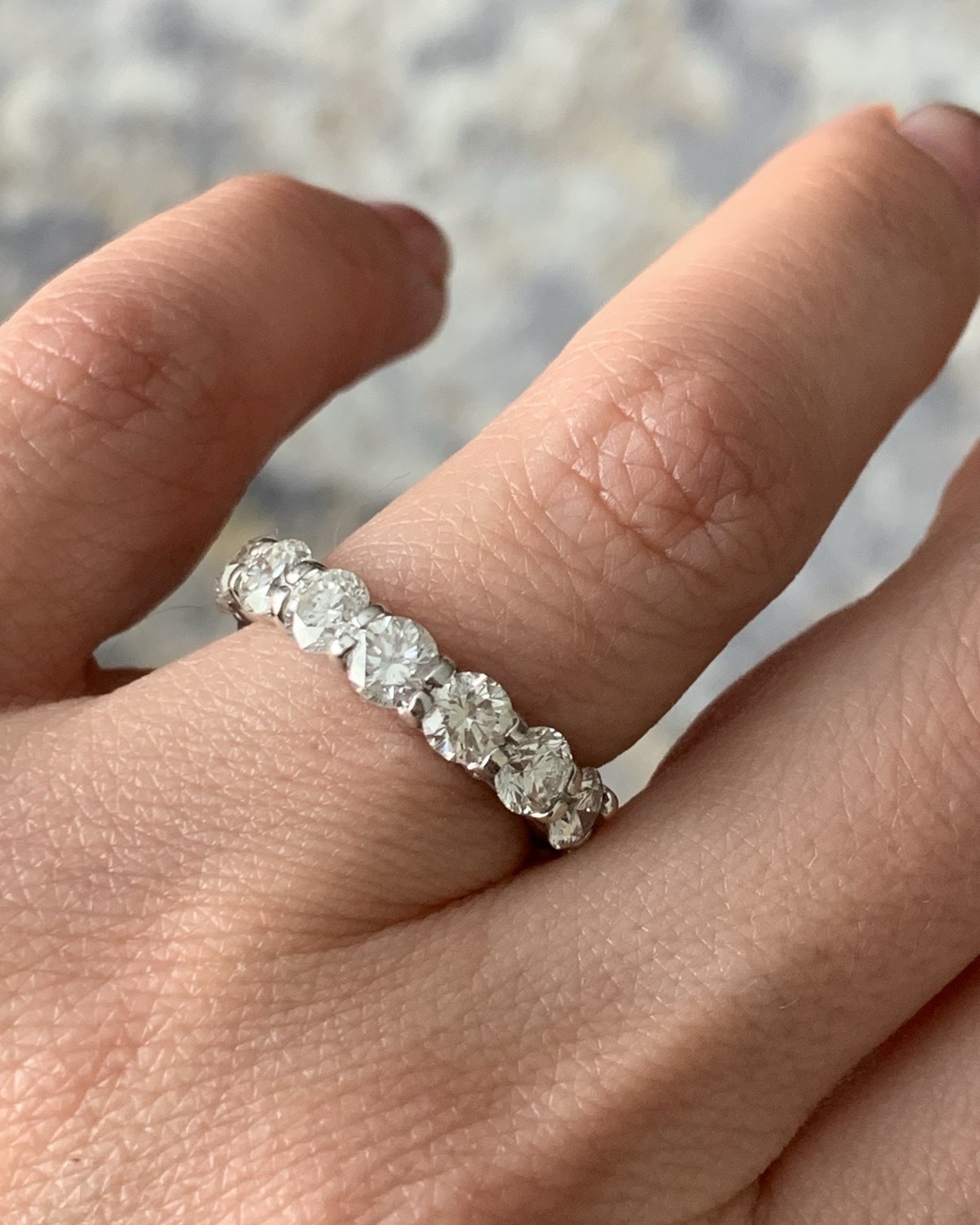 Eternity band set with graduated round brilliant diamonds in shared prongs, worn on the hand