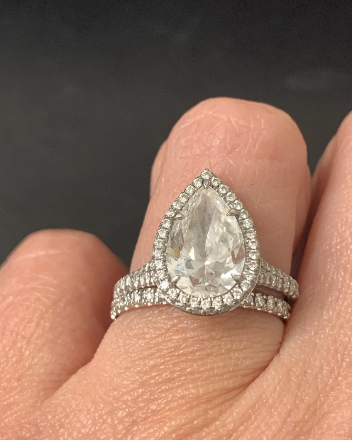 Pear-shape diamond in a pavé halo on a split diamond-set shank, worn with a matching straight pavé band