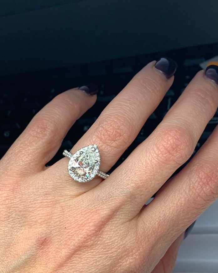 Pear-shape diamond in a fine pavé halo on a slim diamond-set shank, worn on the hand