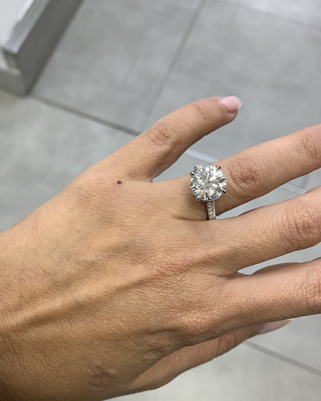 Round brilliant diamond solitaire in a four-prong head on a pavé shank, worn on the hand