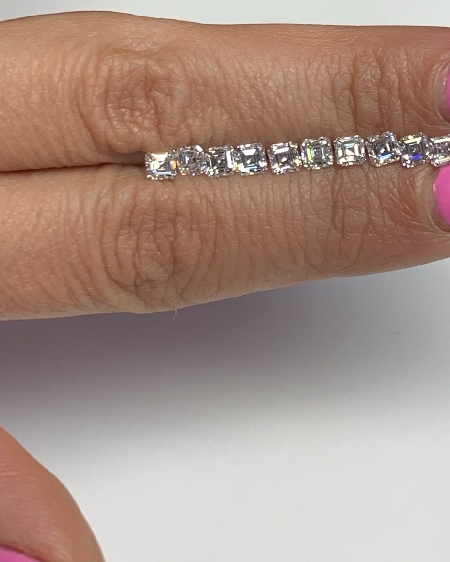 Diamond band set with a single row of square step-cut stones laid edge to edge, held across the fingers