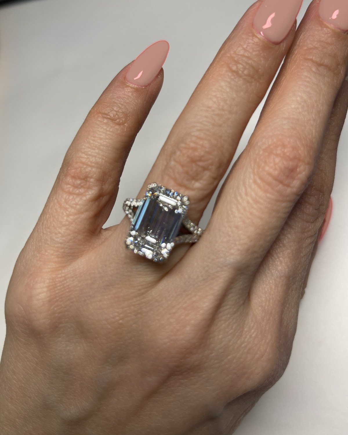 Emerald-cut diamond in corner prongs above a twisted split pavé shank, worn on the hand