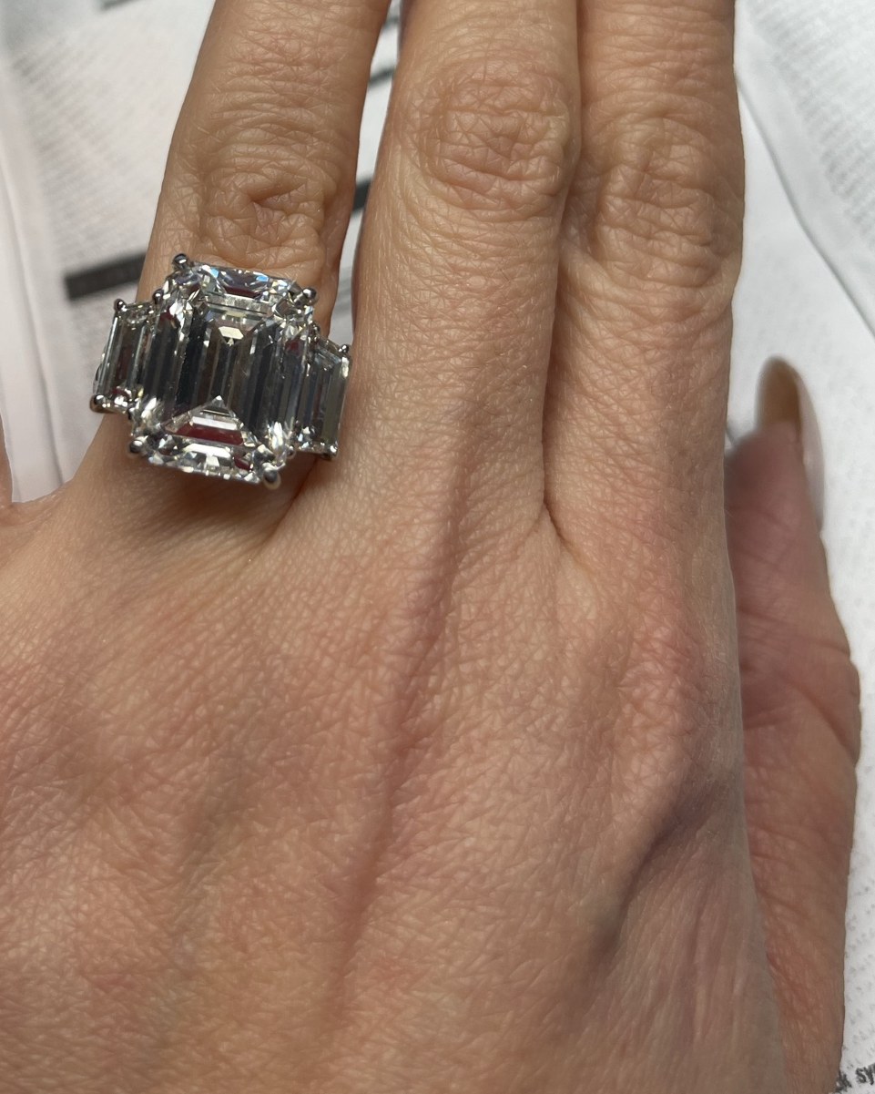 Emerald-cut diamond flanked by two emerald-cut shoulder stones on a plain shank, worn on the hand