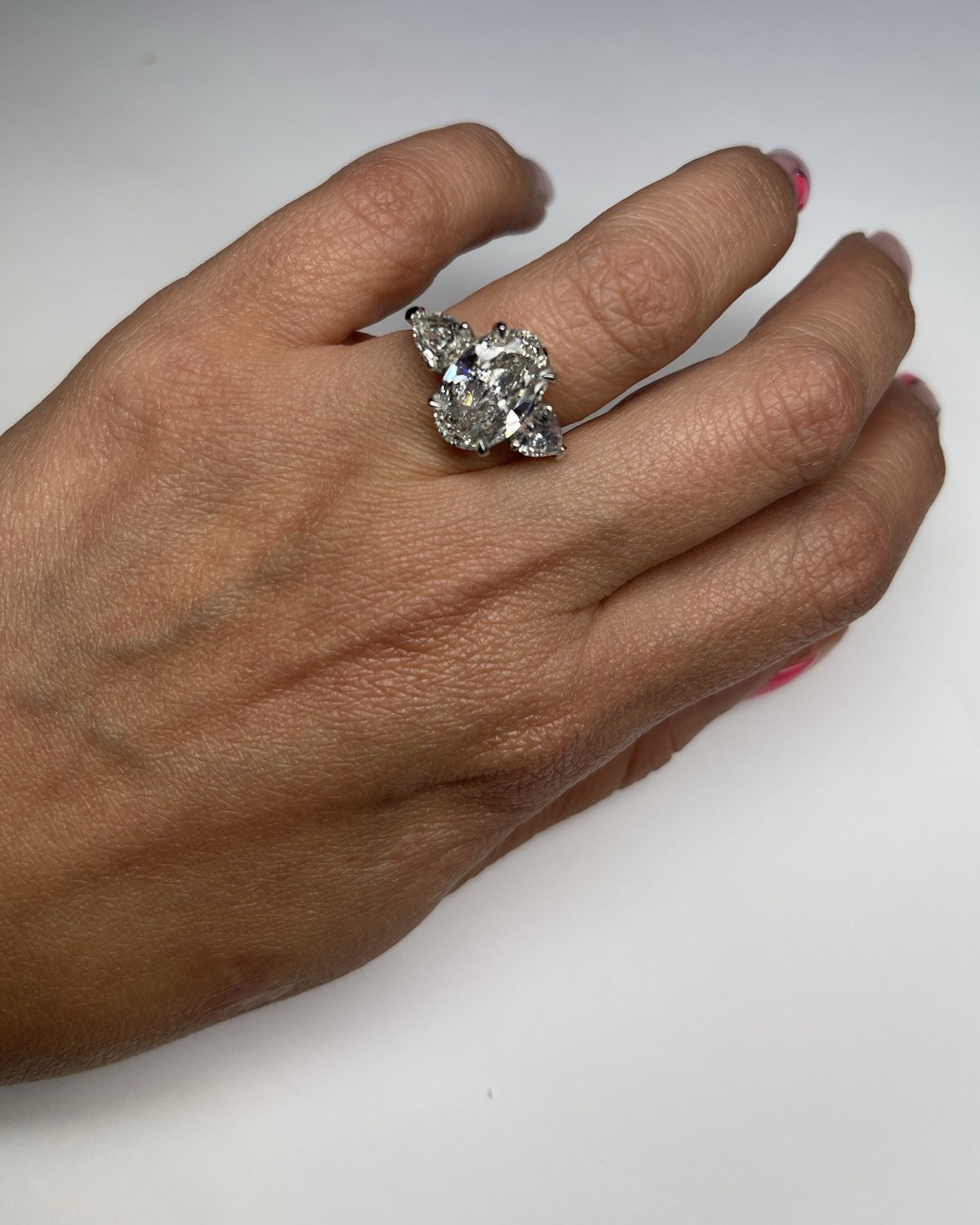 Oval three-stone diamond ring with pear shoulders seen from the back of the hand