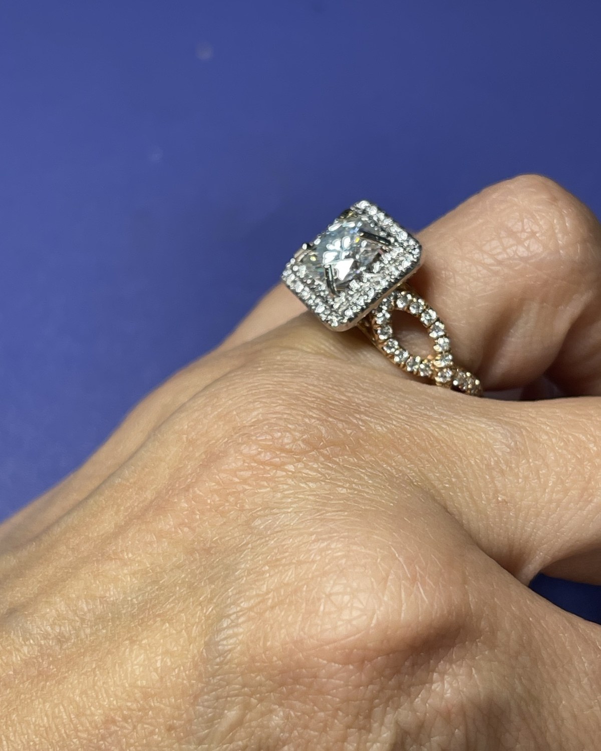 Cushion-cut diamond in a single colorless halo worn with a contoured pavé band curved around the head
