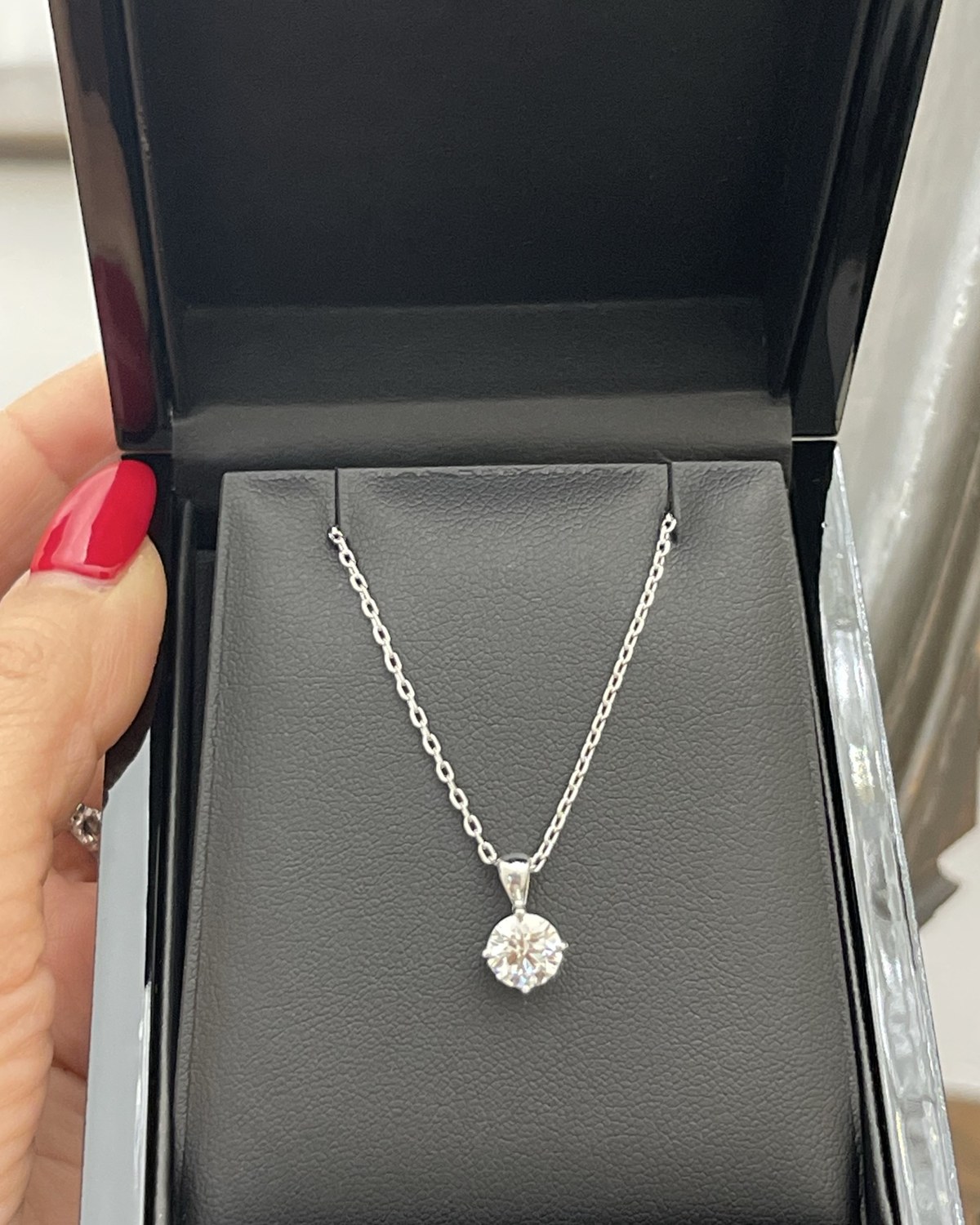 Round brilliant diamond in a six-prong basket on a fine white chain, shown in its presentation box