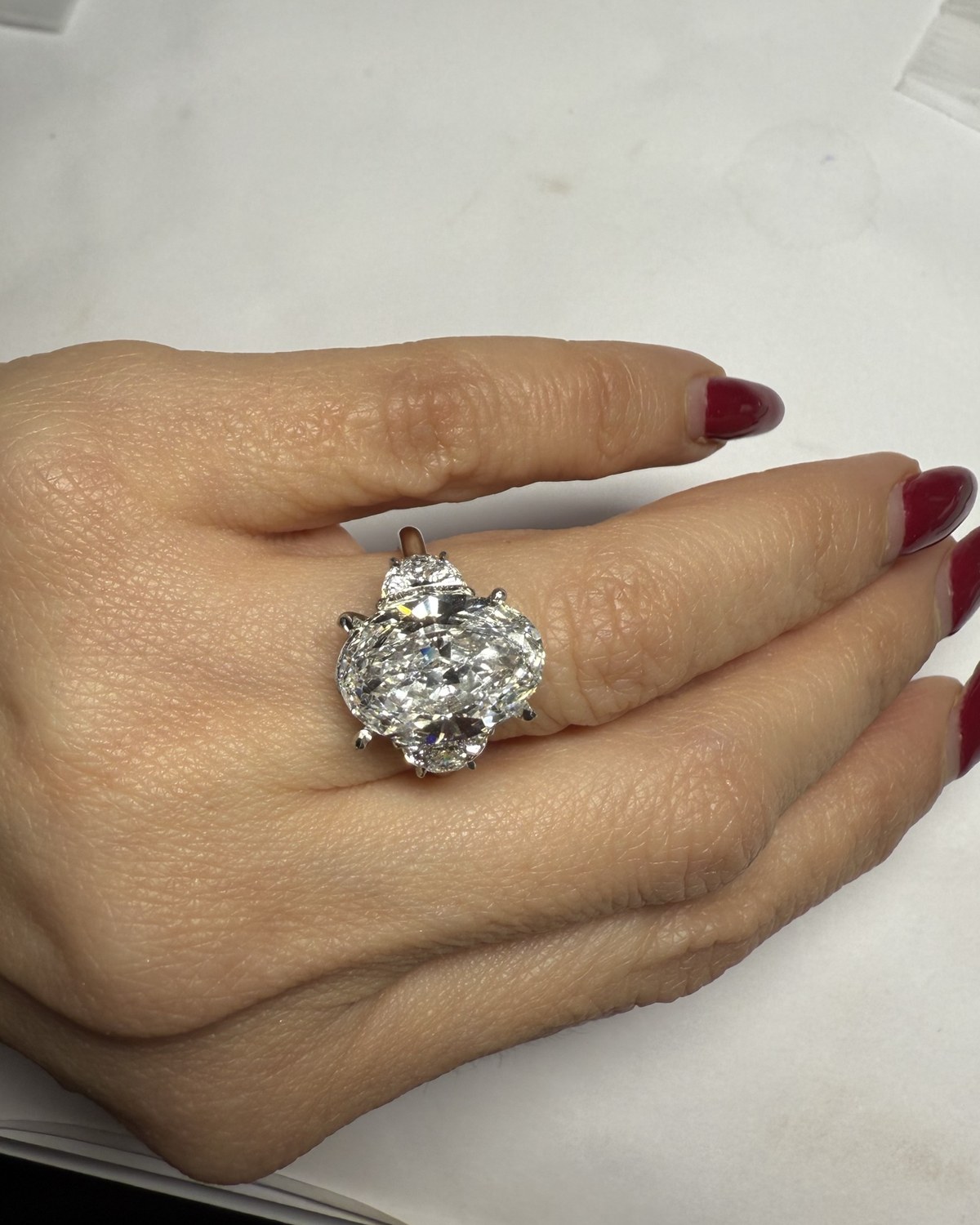 Oval diamond center with half-moon side stones, worn on the hand and seen from a lower angle