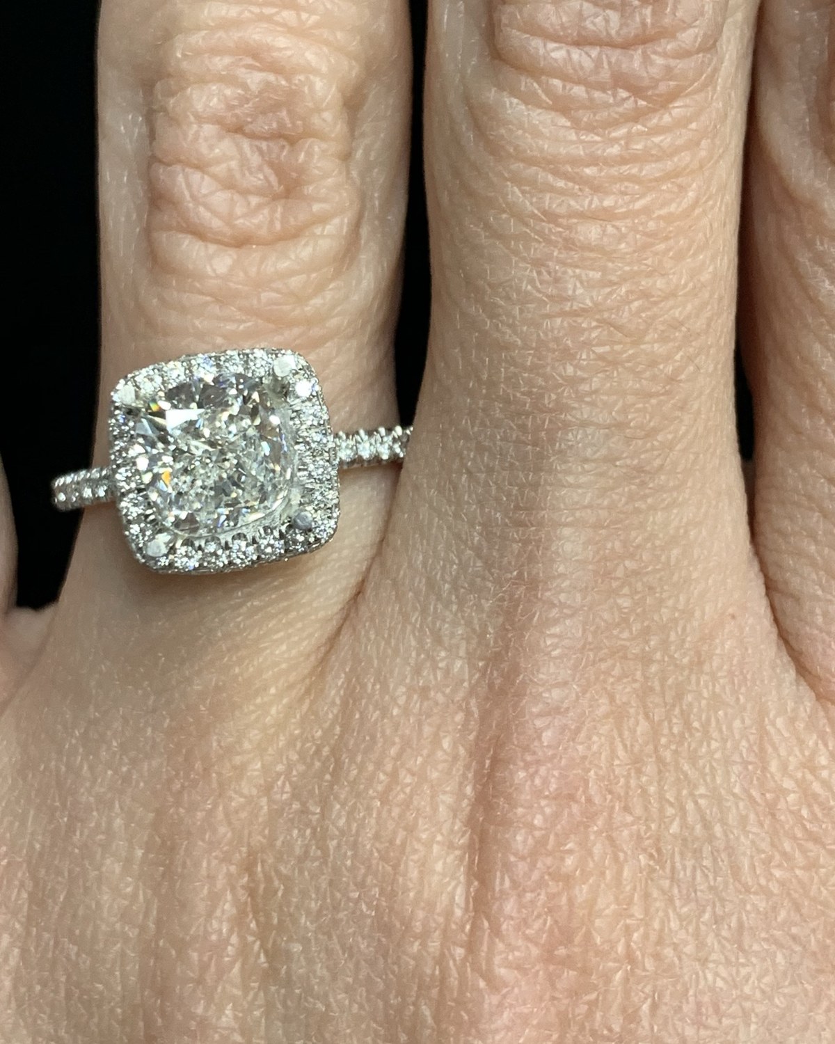 Cushion-outline diamond in a square halo with a pavé shank, worn on the hand