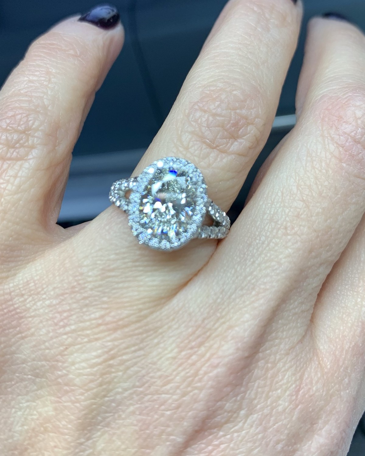 Cushion halo split-shank ring worn on the hand, seen face on
