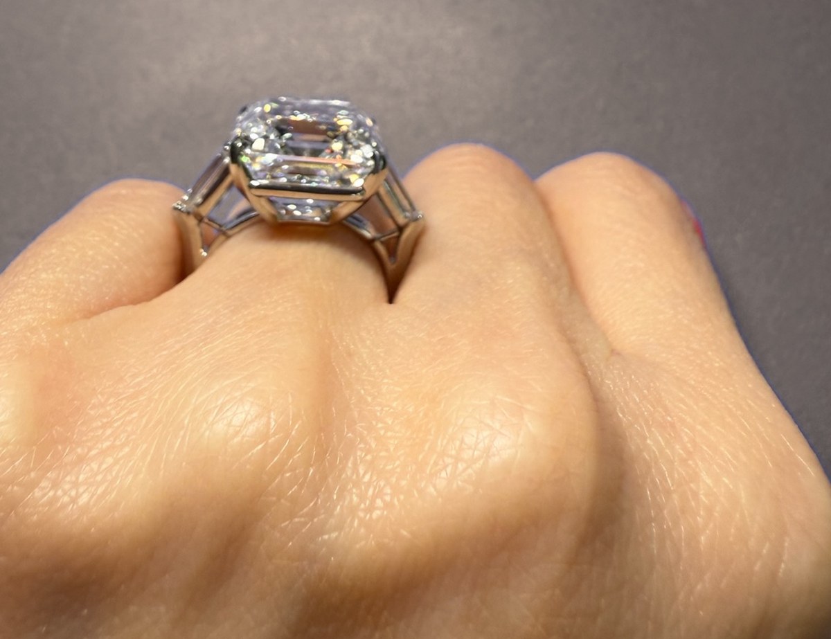 Large step-cut diamond in a three-stone setting with tapered baguettes and an open gallery, worn on the hand