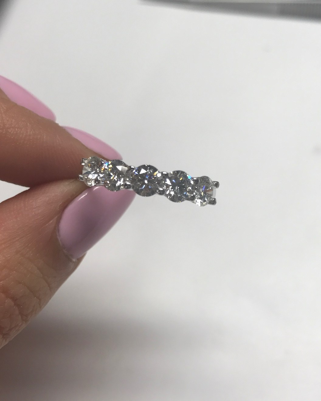 Oval diamond band held at an angle against white, the run of east-west ovals reading across the frame