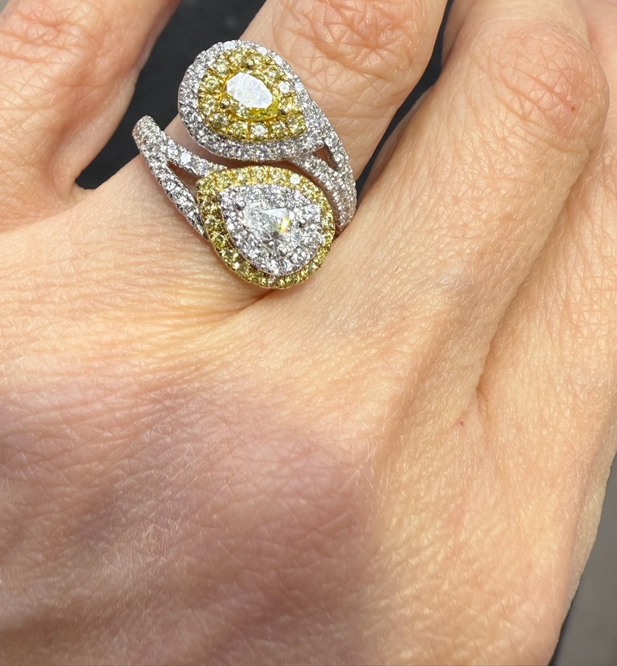 Toi et moi bypass ring with two pear diamonds, each ringed by a halo of fancy yellow diamonds inside a white pavé halo, worn on the hand