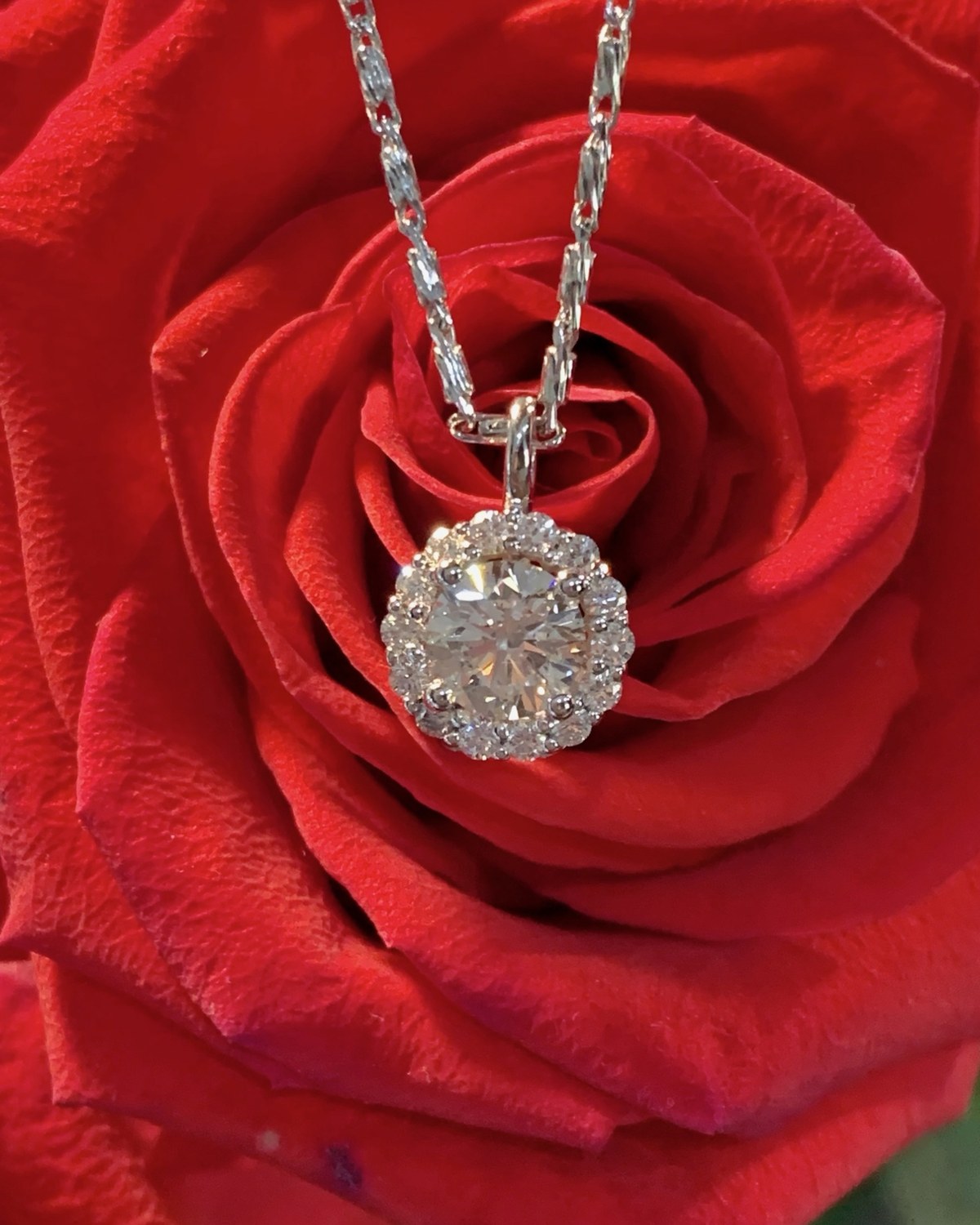 Round floral diamond cluster pendant in a red rose, shown closer with the chain running up the frame