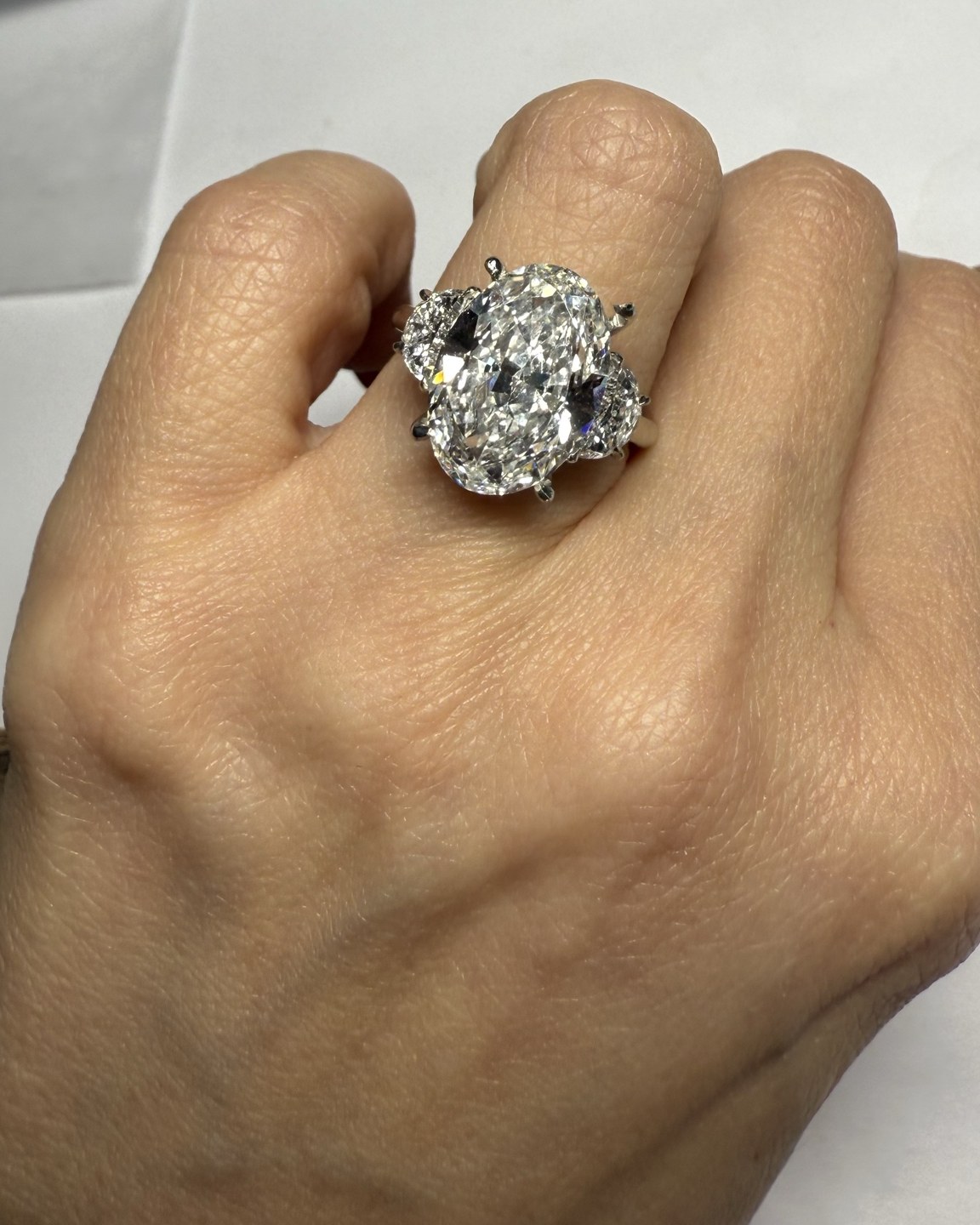 Large oval diamond center with shaped side stones set close against it, worn on the hand