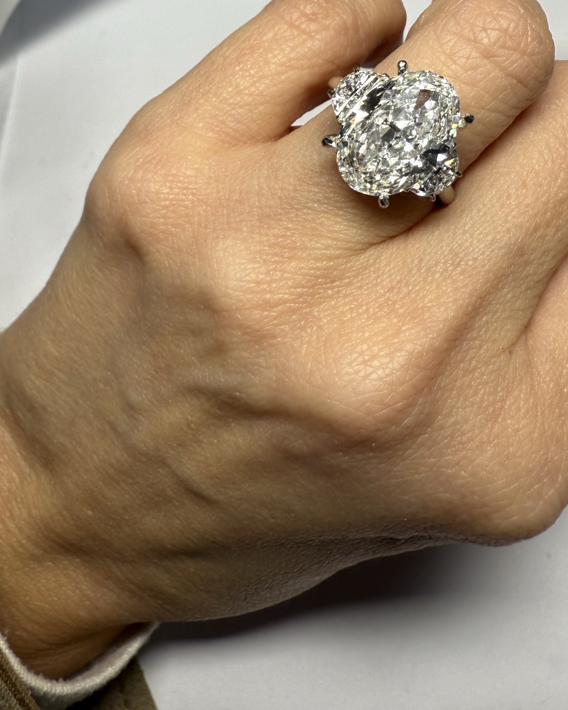 Three-quarter view of the oval center ring with shaped side stones, worn on the hand