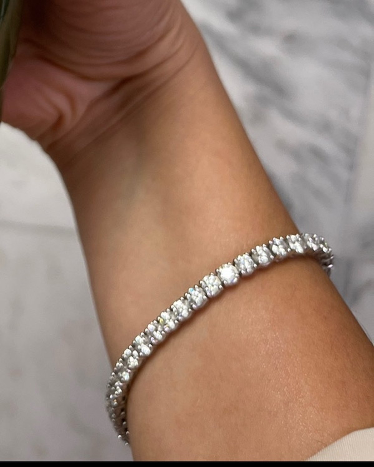 Round diamond line bracelet in white gold worn at the wrist
