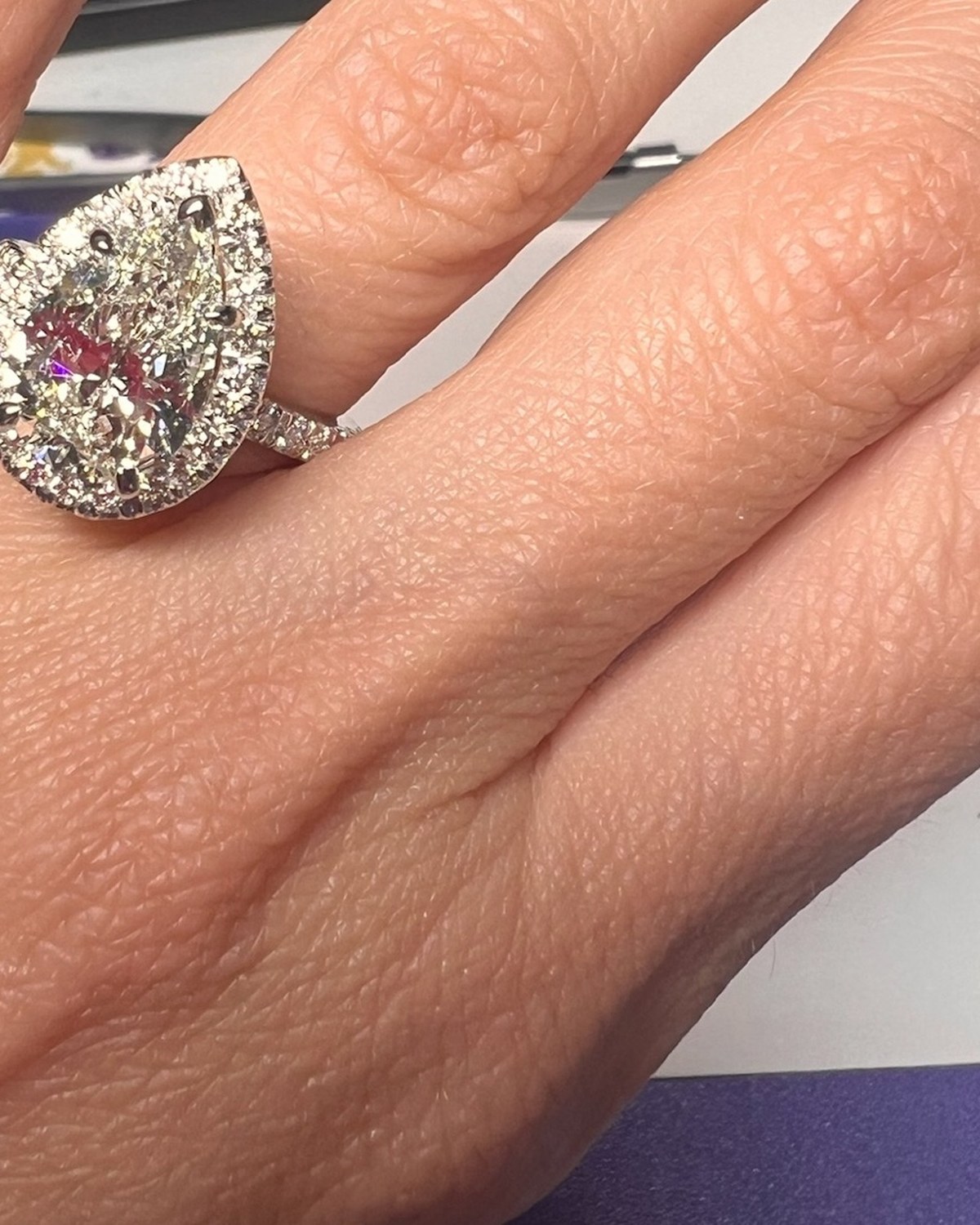 Large pear-shape diamond in a double halo on a pavé shank, worn on the hand