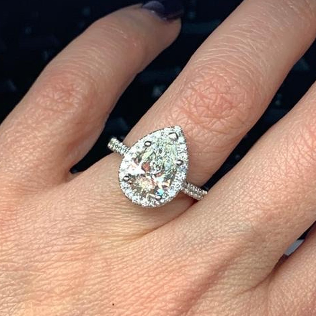 Pear-shape diamond in a pavé halo with a diamond-set shank, worn on the hand