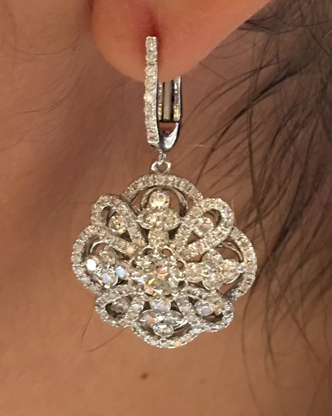 Openwork floral diamond cluster drop earring in warm rose gold, hung from a diamond-set hoop, photographed close at the ear