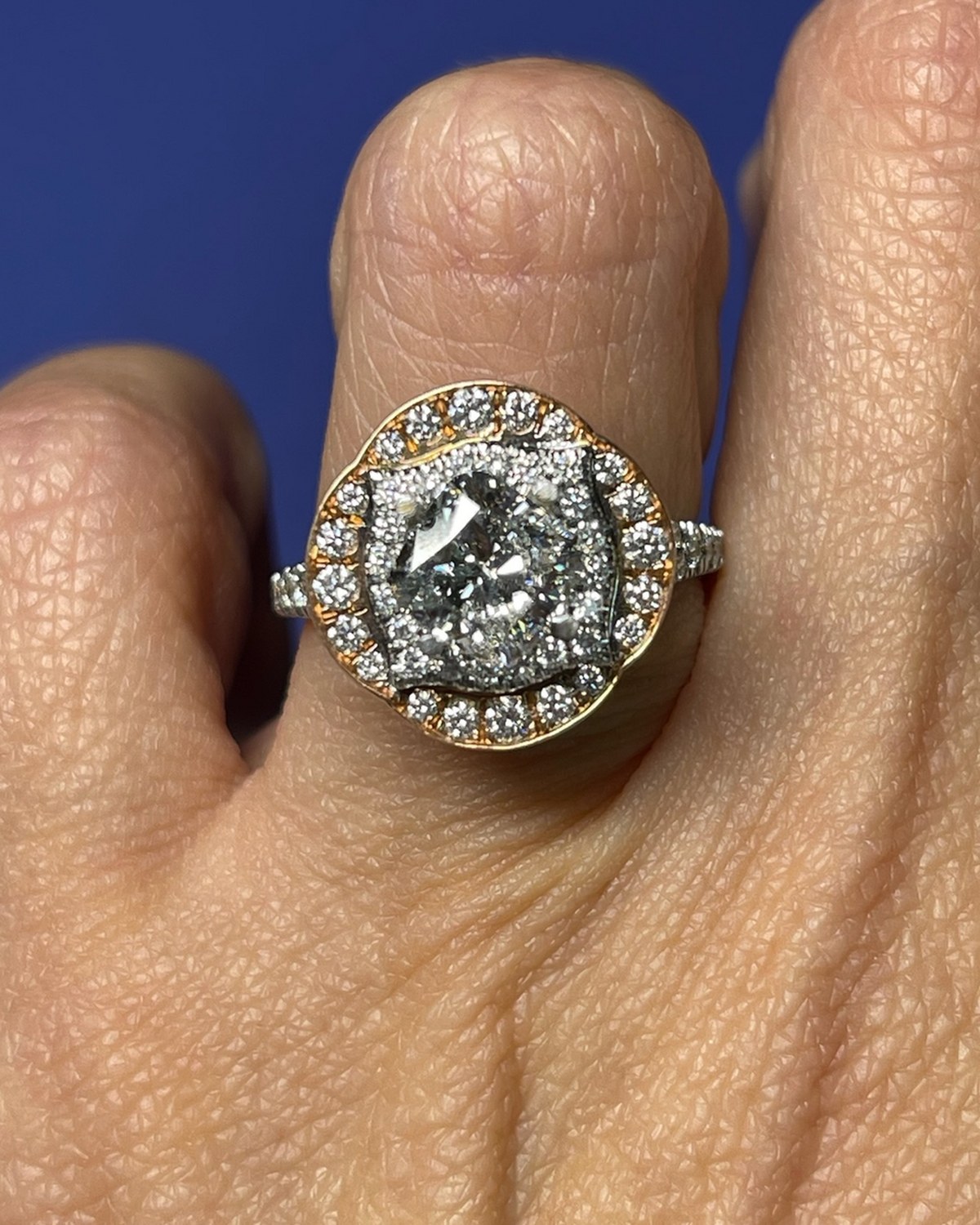 Face-up macro of a cushion diamond inside a white halo framed by a rose gold scalloped halo