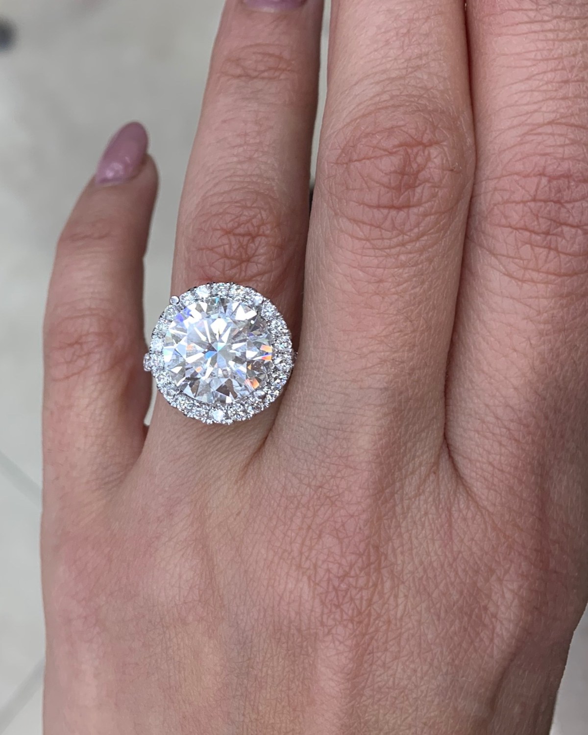 Large round brilliant diamond in a close halo on a fine white gold shank, worn on the hand
