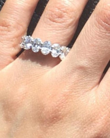 Curved diamond band with graduated stones worn on the finger, photographed close