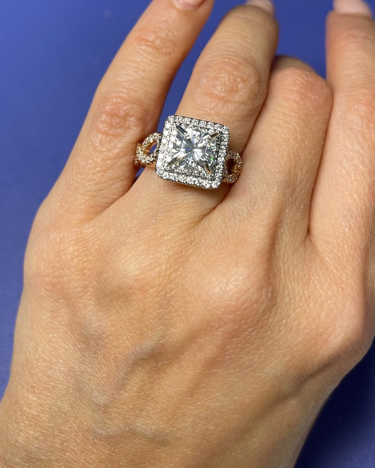 Princess-cut diamond in a white halo on a two-tone rose gold twisted split shank, worn on the hand