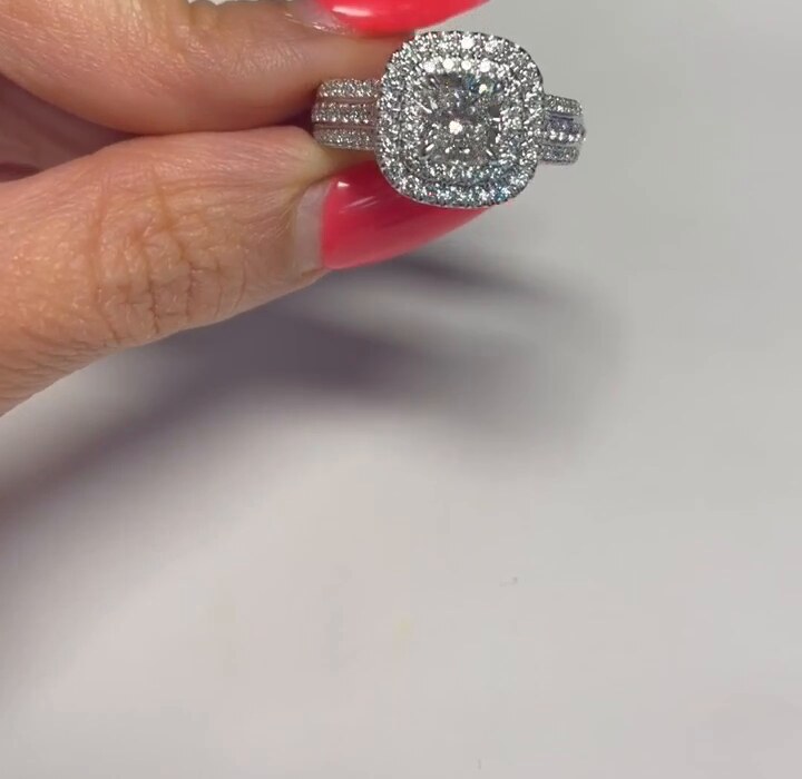 A cushion-cut diamond in a double halo turned slowly in the fingers under an even white light