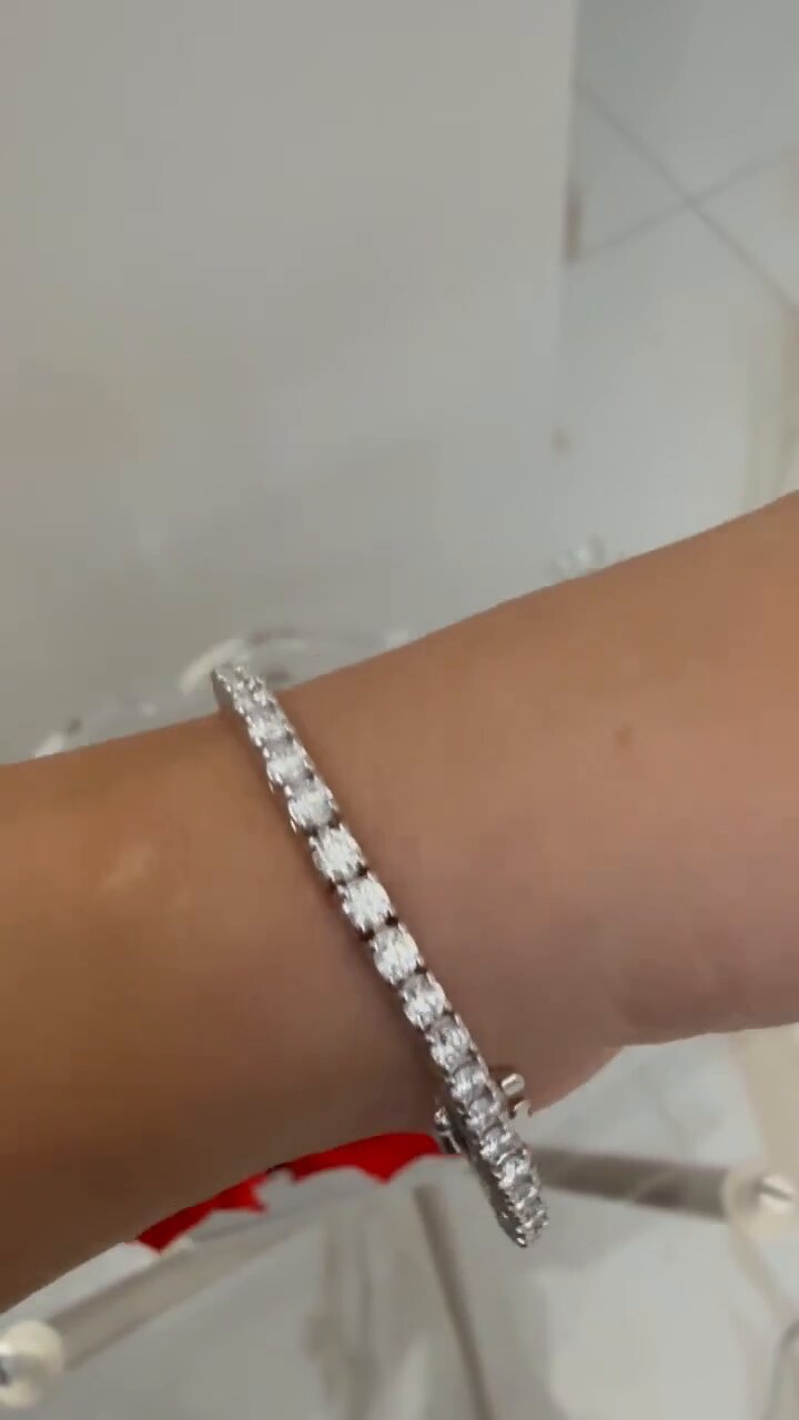 A round diamond tennis bracelet worn at the wrist